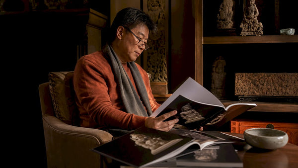 Collector studying Asian sculpture auction catalogues