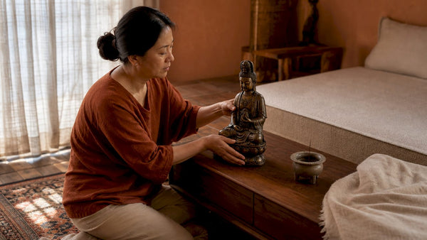 Woman arranging bronze Guanyin in bedroom sanctuary