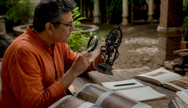 Scholar examining Hindu murti sculpture closely