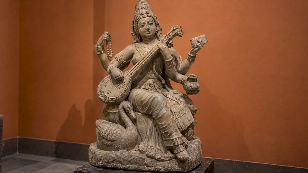 Saraswati sculpture holding four traditional attributes