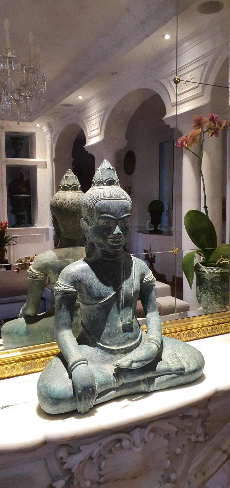 Bronze statue of a seated figure with intricate detailing, placed on a marble surface.